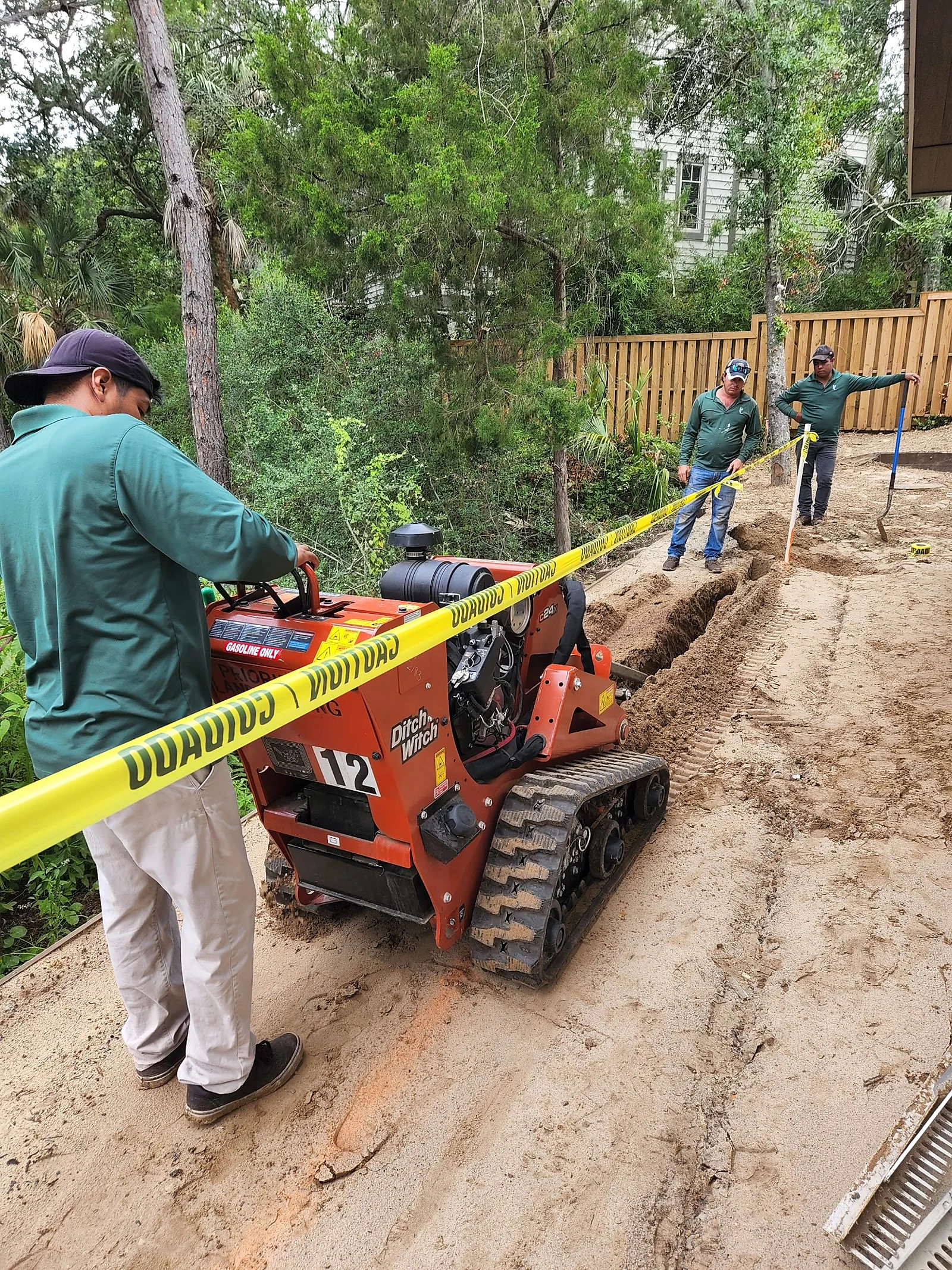 Crew member running a walk-behind trencher for an irrigation line