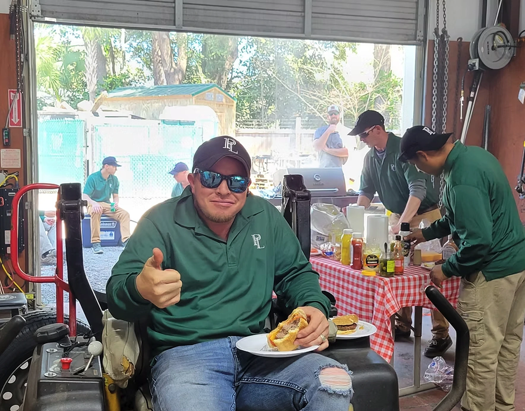 A Priority Landscaping crew member giving a thumbs up during a team cookout at the Charleston shop