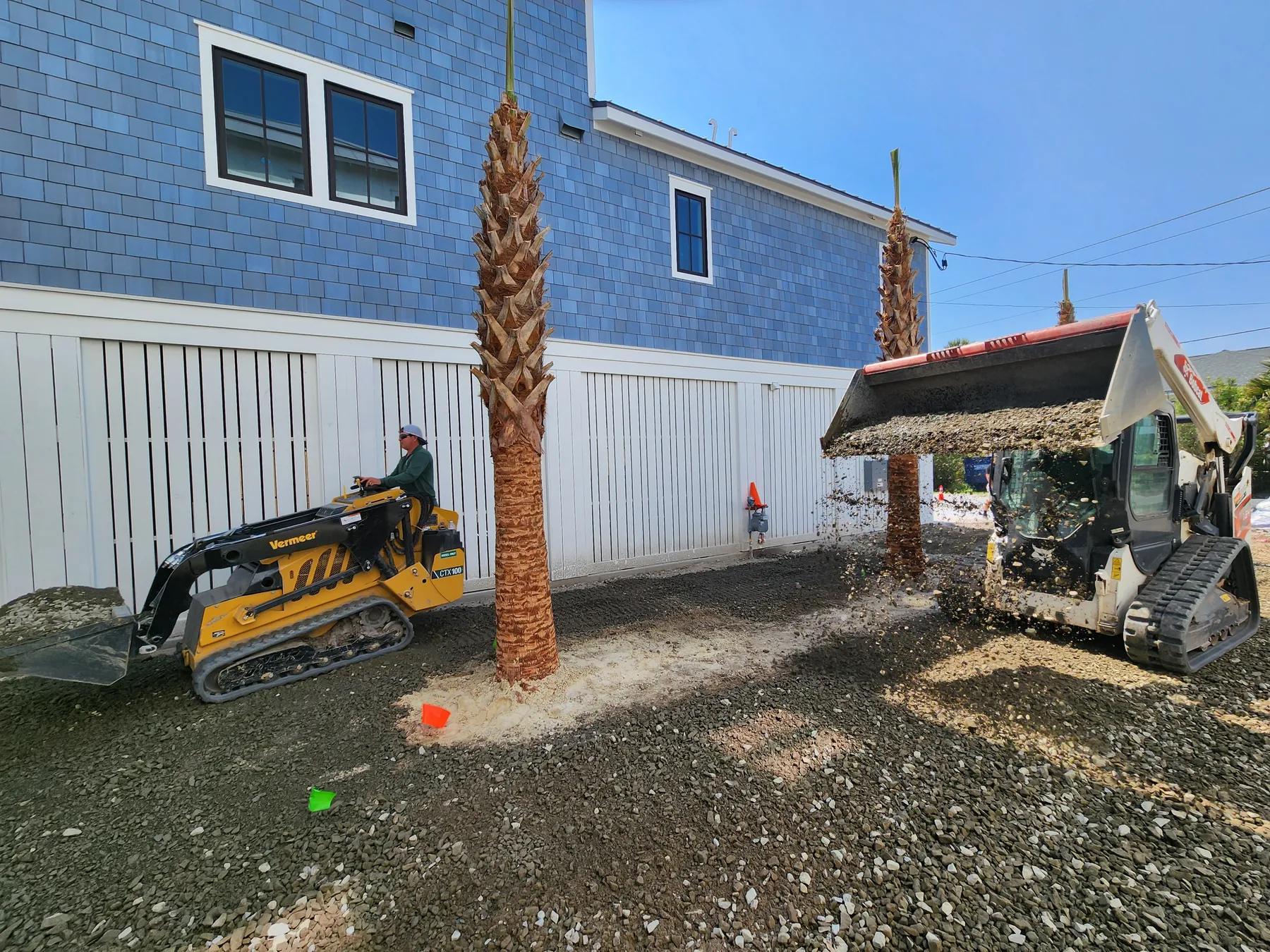 Track loader placing palms during an installation at a Folly Beach home