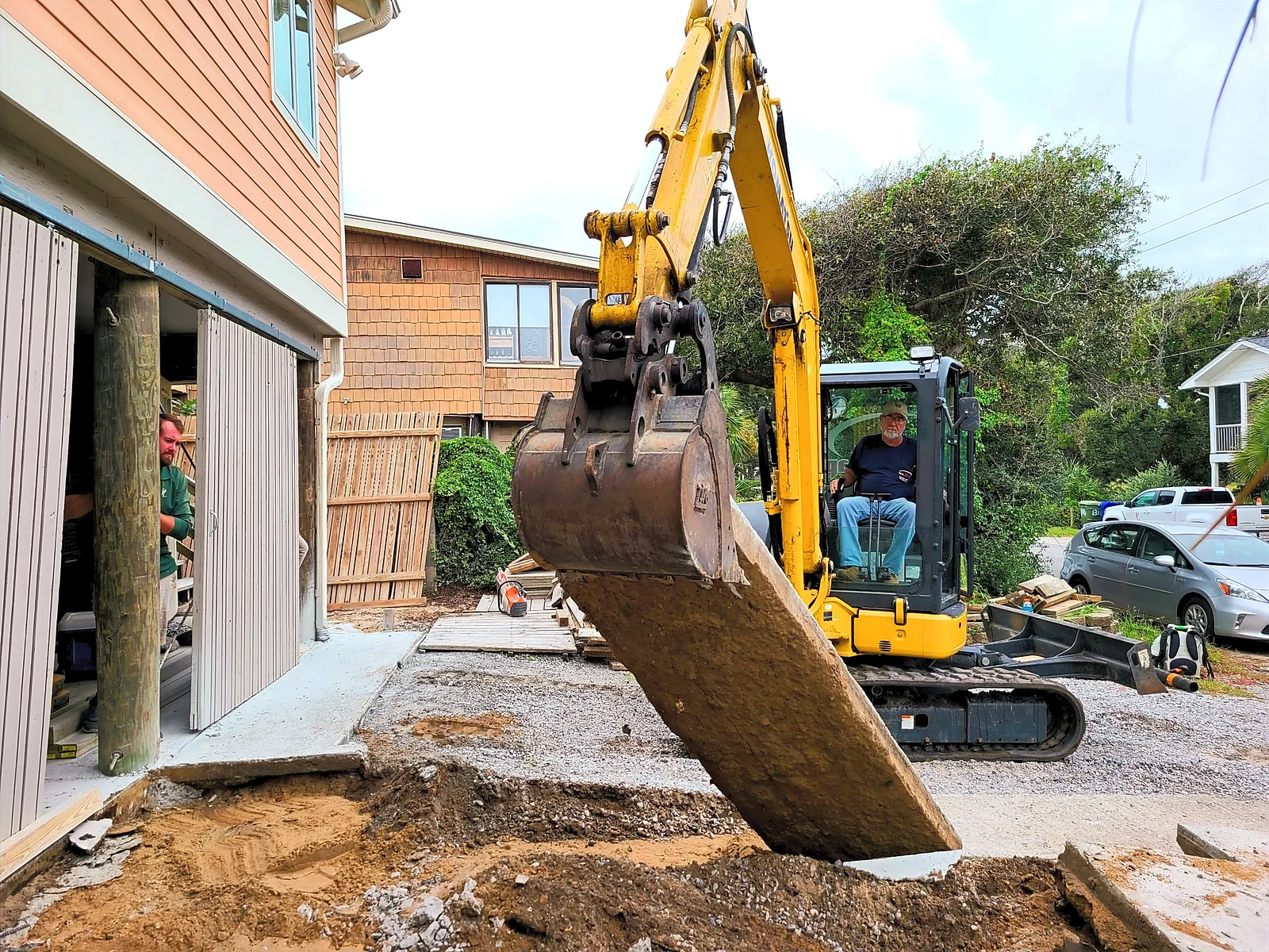Priority Landscaping crew member operating an excavator during a foundation grading job in Charleston